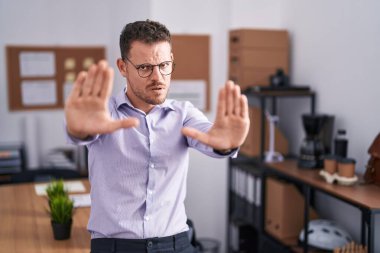 Ofisteki genç İspanyol adam avuç içi hareketlerini durduruyor. Öfkeli ve hayal kırıklığı dolu bir ifade. 