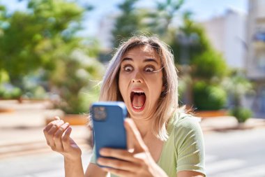 Young woman using smartphone with cheerful expression at park