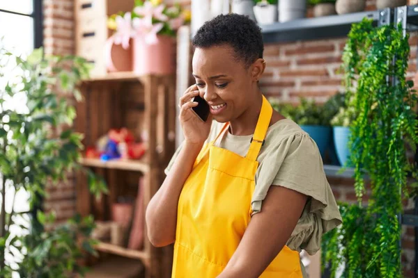 African american woman florist smiling confident talking on smartphone at florist