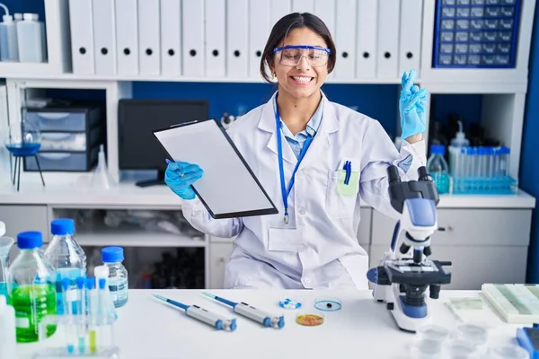 Hispanic Young Woman Working Scientist Laboratory Gesturing Finger Crossed Smiling — ストック写真