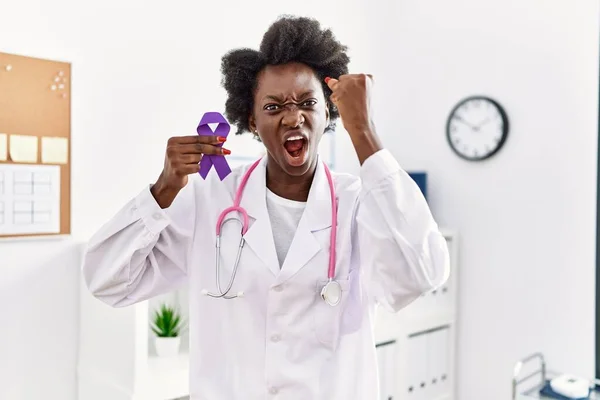 African doctor woman holding purple ribbon awareness at medical clinic annoyed and frustrated shouting with anger, yelling crazy with anger and hand raised
