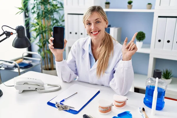 Vacker Tandläkare Kvinna Visar Smartphone Skärmen Ler Glad Pekar Med — Stockfoto