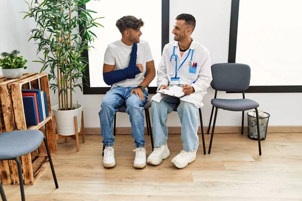 Zwei Hispanische Männer Arzt Und Patient Schreiben Auf Klemmbrett Sitzt — Stockfoto