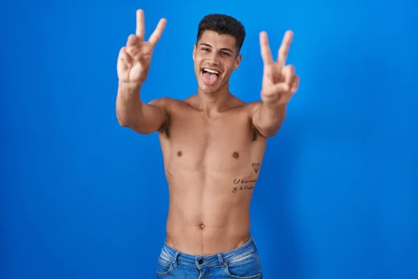 Young Hispanic Man Standing Shirtless Blue Background Smiling Tongue Out — Stock Photo, Image