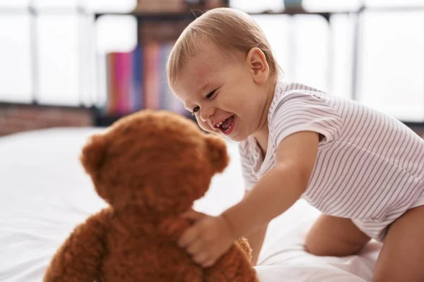 可爱的幼儿与泰迪熊玩耍在卧室的床上 — 图库照片