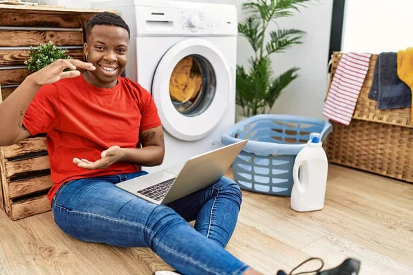 Young African Man Doing Laundry Using Computer Gesturing Hands Showing — Stockfoto