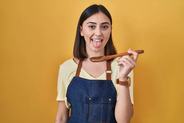 Hispanic Girl Eating Healthy Wooden Spoon Sticking Tongue Out Happy — Zdjęcie stockowe