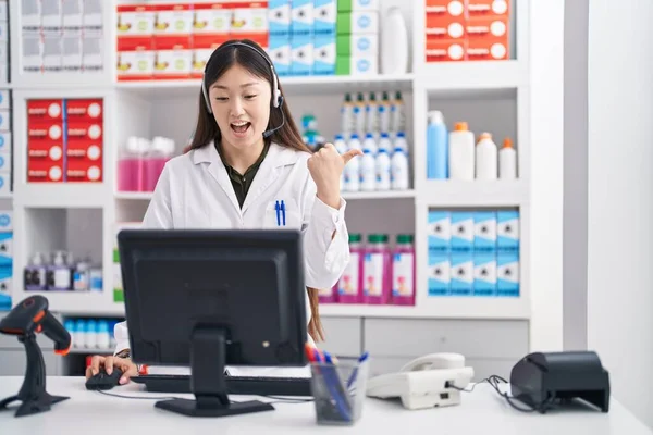 Китайская Молодая Женщина Работающая Аптеке Носит Наушники Указывая Пальцем Вверх — стоковое фото
