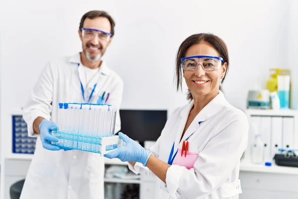 中年男人和女人穿着科学家制服在实验室拿着试管 — 图库照片