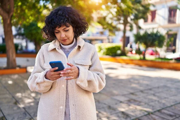 公園で真剣な表情でスマートフォンを使用して若い美しいヒスパニック系女性 — ストック写真