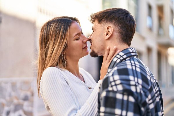 Young man and woman couple hugging each other kissing at street