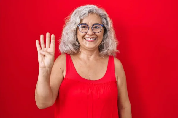 Kırmızı Arka Planda Gri Saçlı Orta Yaşlı Bir Kadın Dört — Stok fotoğraf