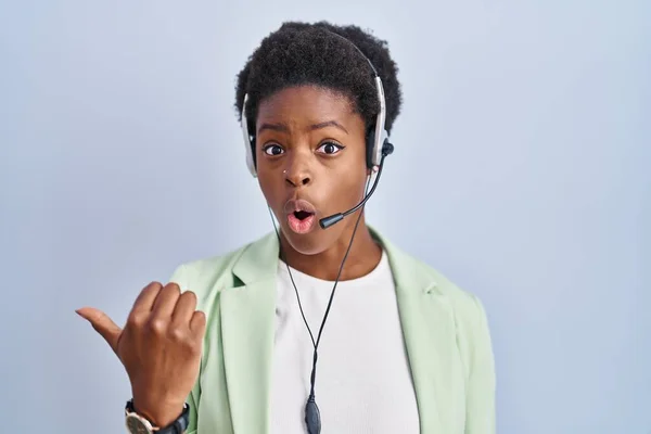 African American Woman Wearing Call Center Agent Headset Surprised Pointing — Stock Photo, Image