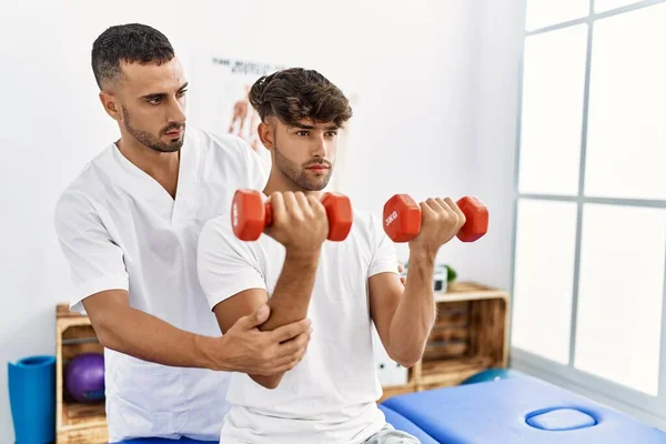 Dois Homens Hispânicos Fisioterapeuta Paciente Tendo Sessão Reabilitação Usando Halteres — Fotografia de Stock