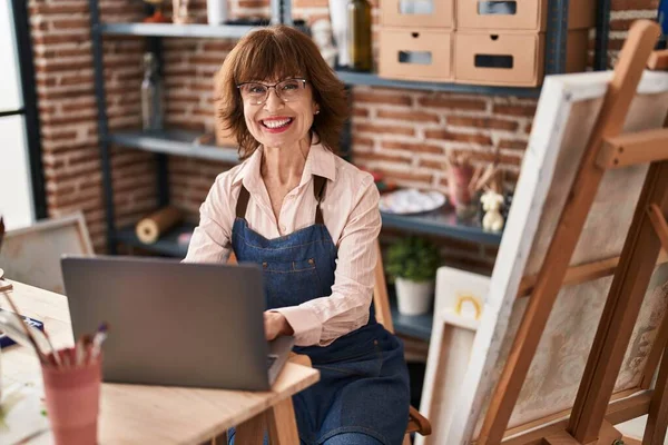 Mujer Mediana Edad Artista Sonriendo Confiado Usando Ordenador Portátil Estudio —  Fotos de Stock