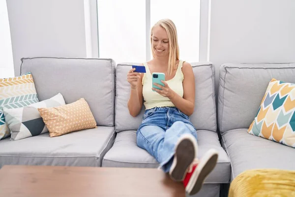 Jovem Loira Usando Smartphone Cartão Crédito Sentado Sofá Casa — Fotografia de Stock