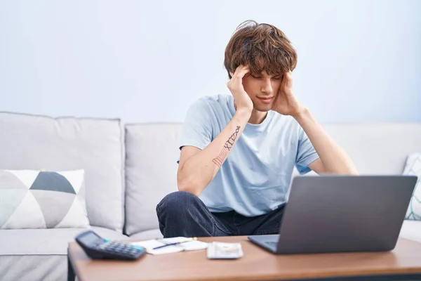 Young blond man stressed using laptop sitting on sofa at home