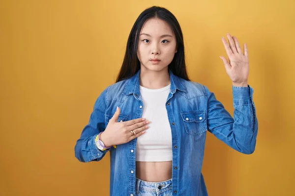 Jonge Aziatische Vrouw Staan Gele Achtergrond Vloeken Met Hand Borst — Stockfoto