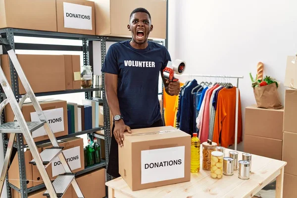 Young African American Volunteer Man Packing Donations Box Charity Angry — Zdjęcie stockowe