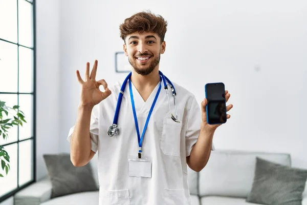 Young Arab Man Wearing Doctor Uniform Stethoscope Holding Smartphone Doing — Stockfoto