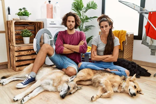 Casal Hispânico Jovem Fazendo Lavanderia Com Cães Céticos Nervosos Desaprovando — Fotografia de Stock