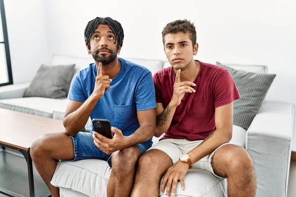 Young Hispanic Men Using Smartphone Sitting Sofa Home Thinking Concentrated — Stock Photo, Image
