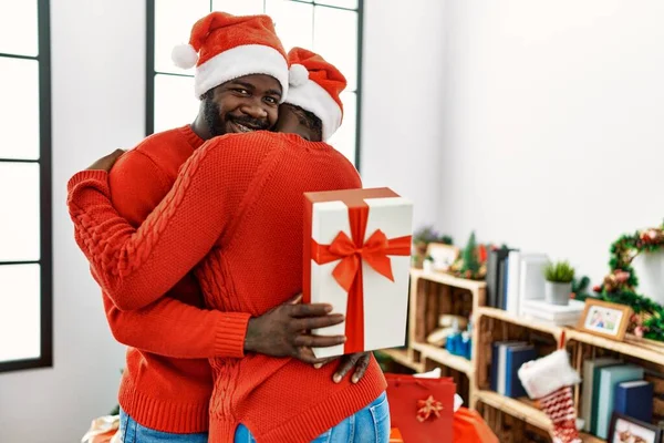 Młoda Afrykańska Para Uśmiecha Się Szczęśliwa Przytula Trzymając Prezent Świąteczny — Zdjęcie stockowe