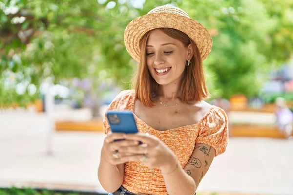 Young Redhead Woman Tourist Wearing Summer Hat Using Smartphone Park — Zdjęcie stockowe