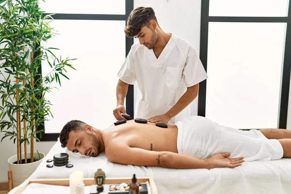 Two Hispanic Men Physiotherapist Patient Having Back Treatment Using Hot — стоковое фото