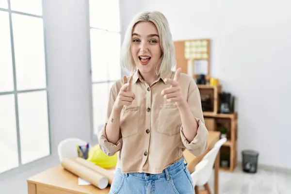 建設事務所で若い美しい白人女性が幸せと面白い顔でカメラに指を指しています 良いエネルギーと振動は — ストック写真