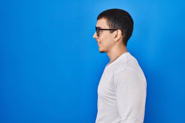 Young arab man wearing casual white shirt and glasses looking to side, relax profile pose with natural face with confident smile. 