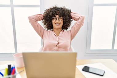 Ortadoğulu genç iş kadını ellerini ofisin başına koyup rahatladı..