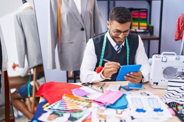 Genç İspanyol terzi gülümsüyor. Terzi dükkanında kendine güvenen çizimler yapıyor.