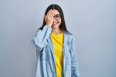 Mavi arka planda duran genç İspanyol kadın bir gözünü eliyle kapatıyor, yüzünde kendine güvenen bir gülümseme ve sürpriz bir duygu var.. 