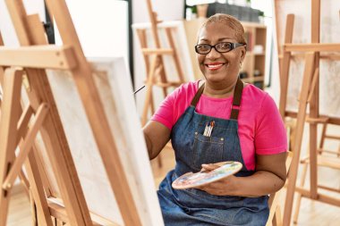 Kıdemli Afro-Amerikan kadın sanat stüdyosunda kendine güvenen çizimler yapıyor.