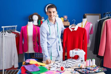 Genç İspanyol terzi dikiş atölyesinde deftere tişört yazıyor.