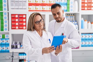 Man and woman pharmacist using touchpad working at pharmacy