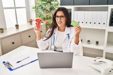 Genç İspanyol doktor kadının elinde anatomik kadın organı ve doğum kontrol hapları var. Bilgisi yok ve kafası karışık. şüphe kavramı. 