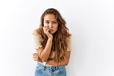 Arka plan gergin ve gergin görünürken ve elleri ağızdan tırnak yerken, güzel İspanyol kadın tecrit altında duruyor. anksiyete. 