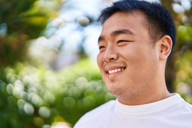 Young chinese man smiling confident standing at park