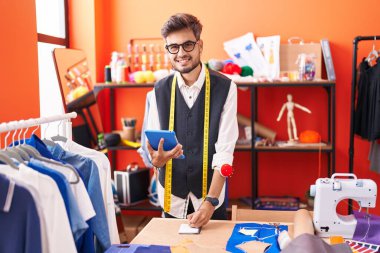 Genç İspanyol terzi atölyedeki deftere dokunmatik not defteri kullanıyor.