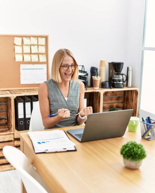 Ofiste çalışırken gülümseyen genç sarışın kadın.