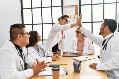 Group of doctor smiling happy and looking parters high five at clinic office.