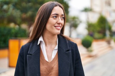 Genç, güzel, İspanyol bir kadın, gülümsüyor. Parkta kendine güveniyor.