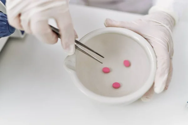 研究室で錠剤を保持する科学手袋を身に着けているシニア白髪の女性 — ストック写真