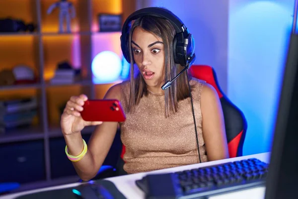 Young Hispanic Woman Playing Video Games Smartphone Scared Amazed Open — стоковое фото