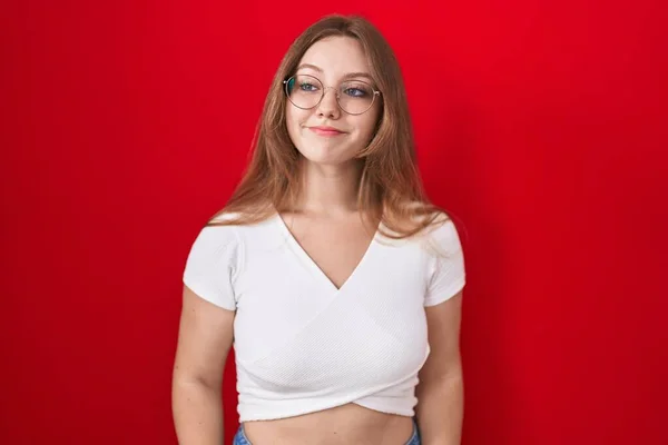 Νεαρή Καυκάσια Γυναίκα Στέκεται Πάνω Από Κόκκινο Φόντο Χαμογελώντας Κοιτάζοντας — Φωτογραφία Αρχείου