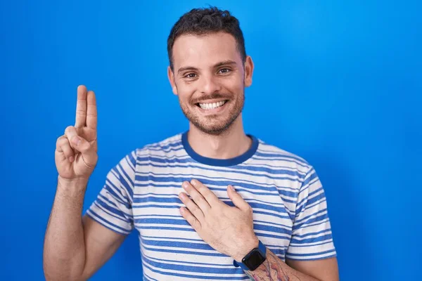 Jovem Hispânico Sobre Fundo Azul Sorrindo Jurando Com Mão Peito — Fotografia de Stock