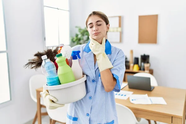 Jovem Loira Vestindo Uniforme Limpeza Segurando Produtos Limpeza Tocando Pescoço — Fotografia de Stock