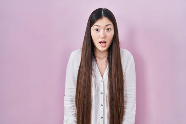 中国の若い女性はピンクの背景の上に立って恐れて 驚きと驚きの表情でショックを受けました 恐怖と興奮した顔 — ストック写真